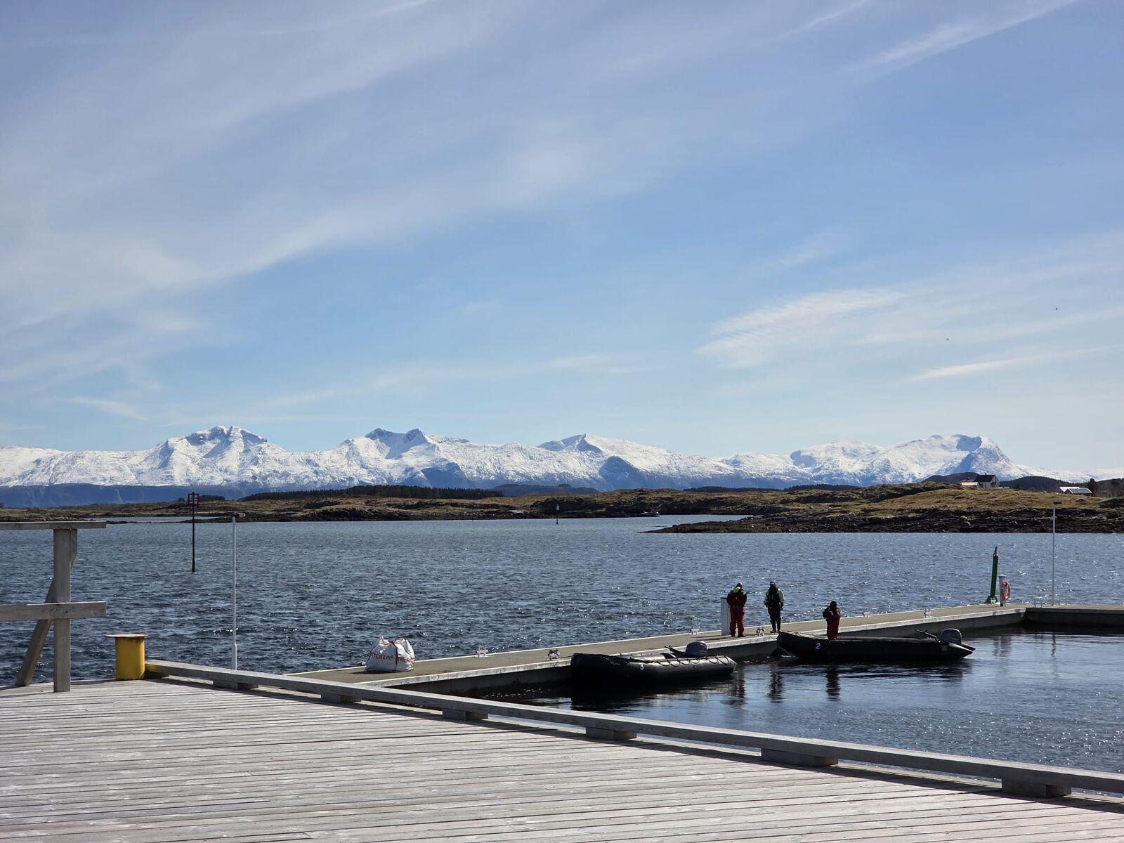 Brygge og snødekte fjell langs Helgelandskysten